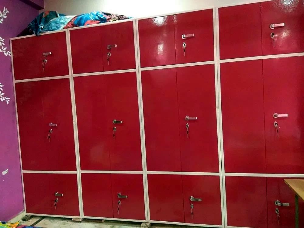 कमरे की पूरी दीवार में लगी लाल स्टील अलमारी, कई दरवाज़ों वाली